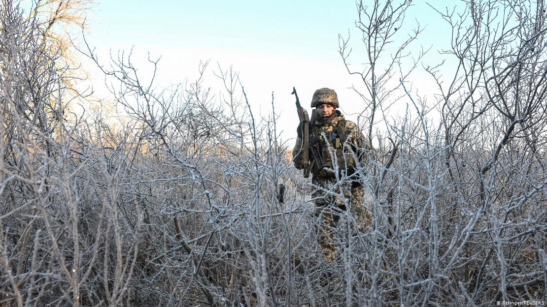 Një ushtar ukrainës duke kaluar mes disa pemëve me ngricë