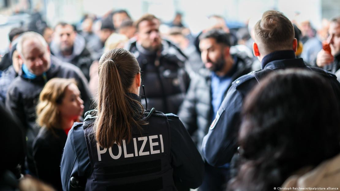 Polizeibeamte sichern den Bereich vor der Bank, während Kunden protestieren. Polizeibeamte sichern den Bereich vor der Bank, während Kunden protestieren.