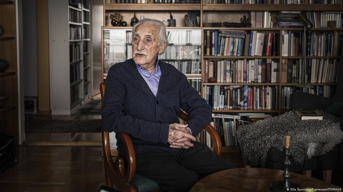 Leon Weintraub sentado en su sala en su departamento en Suecia. 