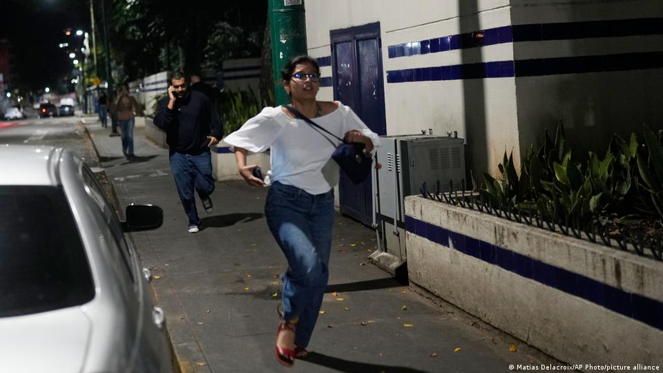 Gente corriendo por la calle, algunos llamando por sus celulares.