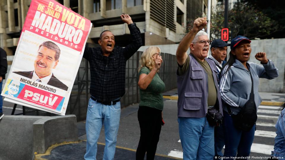 Un grupo de manifestantes corea consignas enarbolando un cartel electoral con la cara de Maduro.