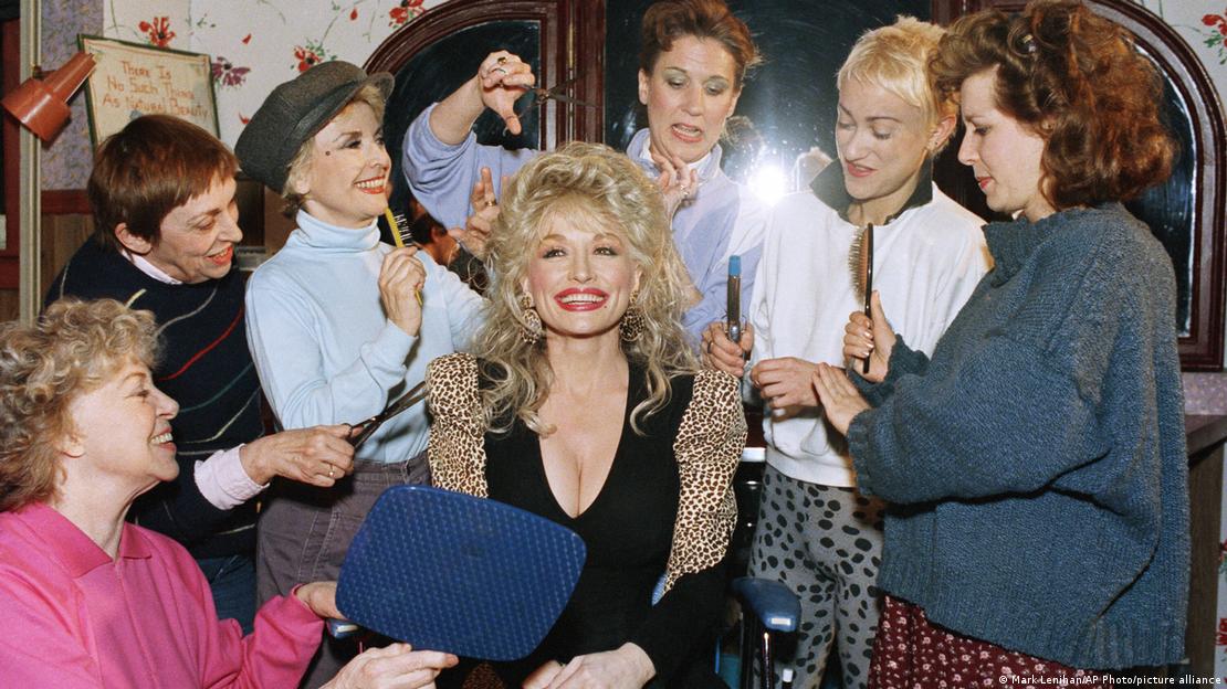 Dolly Parton, who is slated to appear in the film version, gets a mass hairdo as she visits the Broadway show 'Steel Magnolias': 6 women surround her with brushes and scissors.