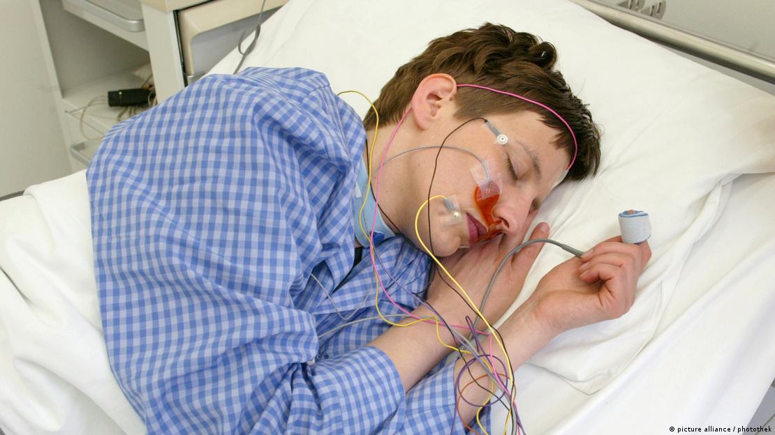 Homem dorme em laboratório do sono com cabos e sensores conectados à sua cabeça 