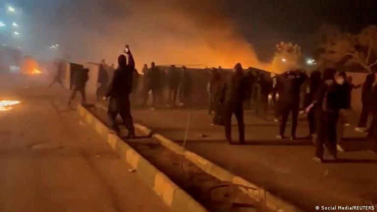 İran'ın Meşhed kentindeki hükümet karşıtı gösterilerde protestocuların arkasından dumanlar yükseliyor