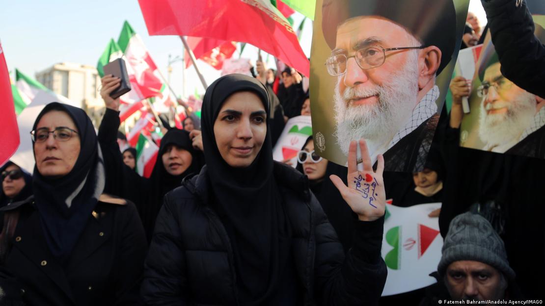 Rejim destekçisi kalabalık arasında Ali Hamaney resimleri ve İran bayraklarıyla poz veren İranlı kadınlar.