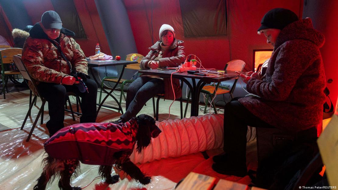 La gente se calienta en una tienda de campaña proporcionada por los servicios de emergencia para los residentes de Kiev, cuyos apartamentos se han quedado sin calefacción mientras los temperaturas están por debajo de los cero grados, tras ataques rusos a la infraestructura energética ucraniana. 
