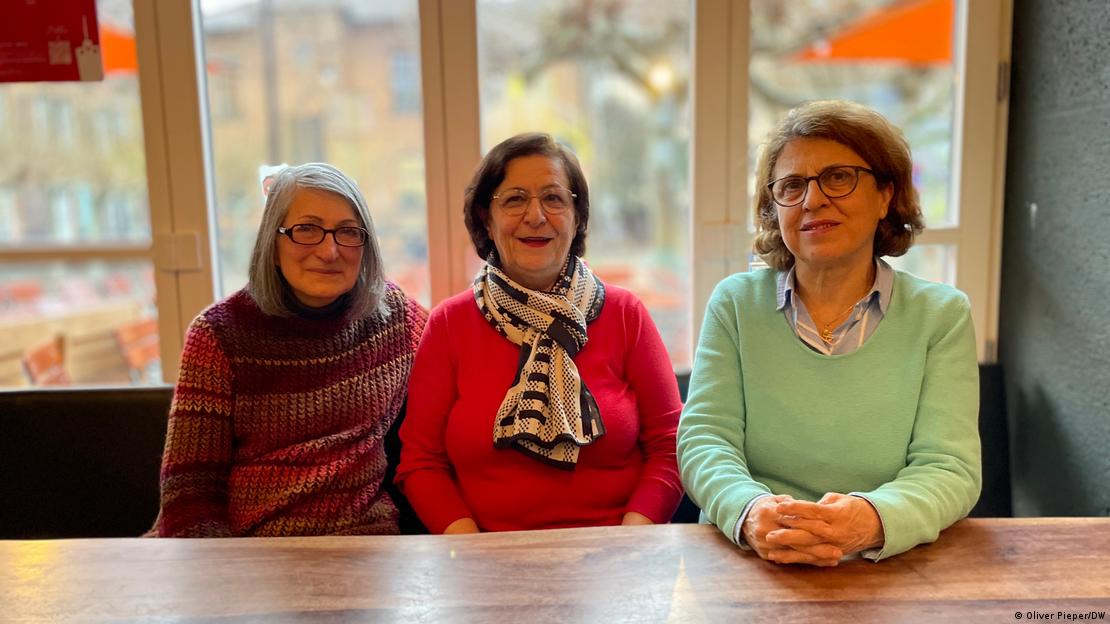 Drei Frauen sitzen an einem Tisch vor einem Fenster