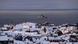 Navio militar dinamarquês navega na costa da Groenlância, em frente a casas cobertas de neve Navio militar dinamarquês navega na costa da Groenlância, em frente a casas cobertas de neve