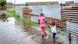 Crianças atravessam as águas das cehias num bairro de Maputo Crianças atravessam as águas das cehias num bairro de Maputo