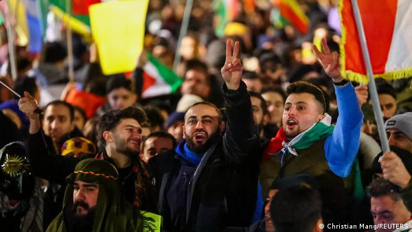 Protesto gösterisinde kalabalık ortasında özgürlük işareti yapan iki kişi