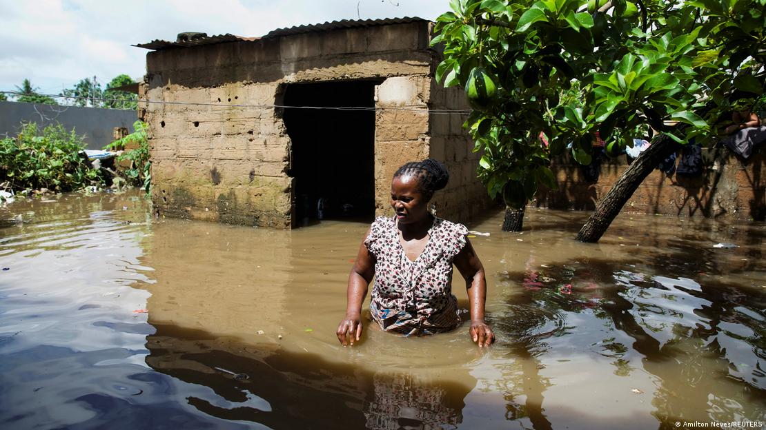 Mulher caminha em área inundada em Moçambique 
