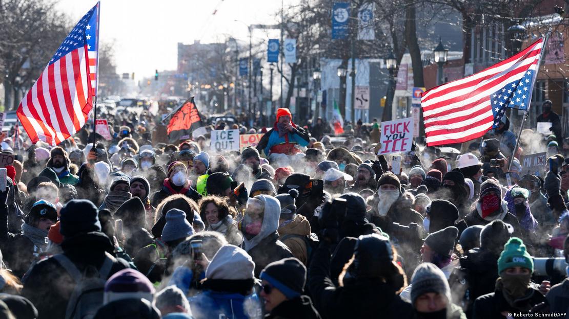 Multidão na rua com duas bandeiras dos EUA