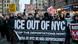 Multidão em passeata na rua com uma grande faixa negra com letras brancas: "ICE out of NYC" e "Stop the deportations now!"