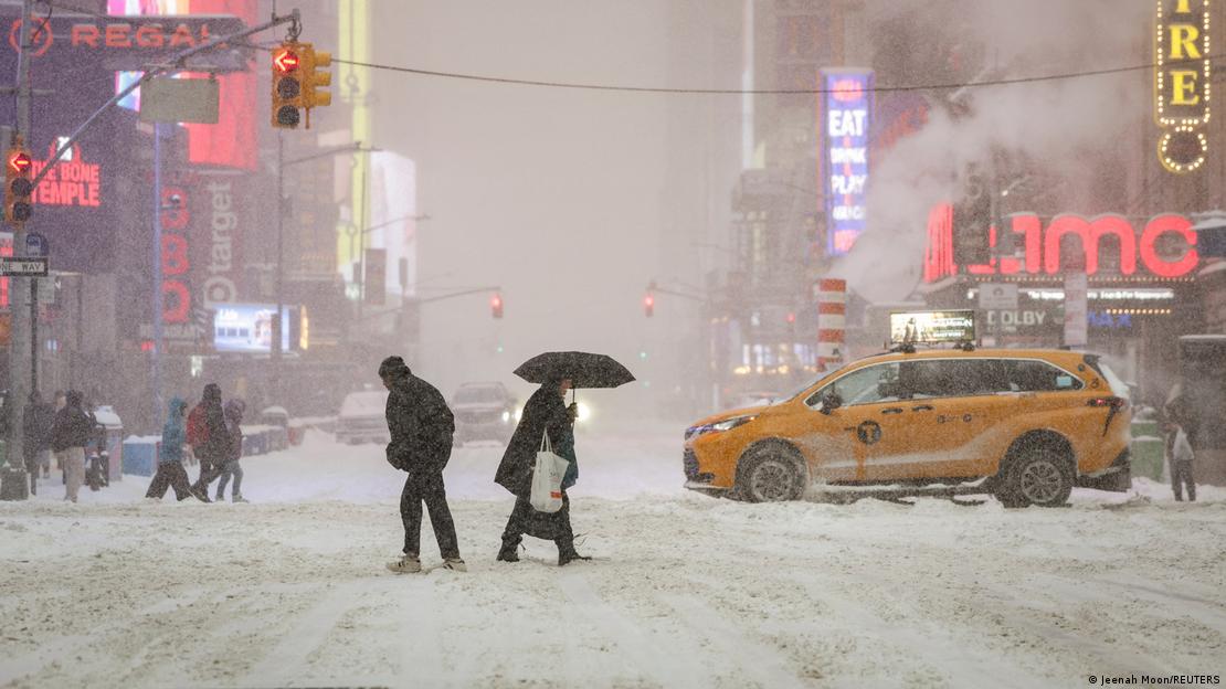 Peatones cruzan Times Square, en Nueva York, en medio de fuertes nevada, con el suelo congelado y poca visibilidad.
