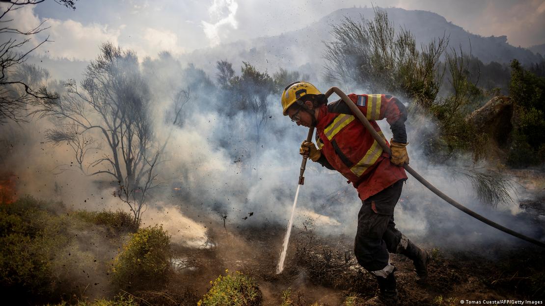 Bombeiro maneja mangueira para conter incêndio na Argentina