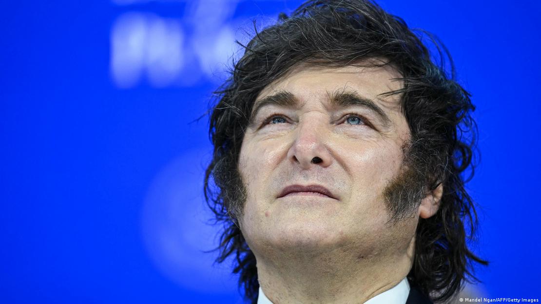 Primer plano de Javier Milei, que mira hacia arriba, sobre un fondo azul.