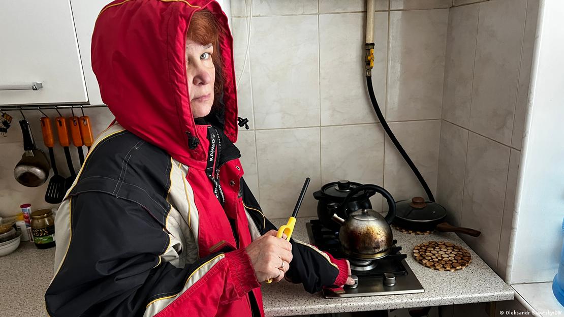 Sviatoslava, una residente de un edificio de Kiev que hace semanas carece de calefacción, prenda una de las hornallas de su cocina para calentar un poco el lugar, abrigada con una chaqueta gruesa con capucha.