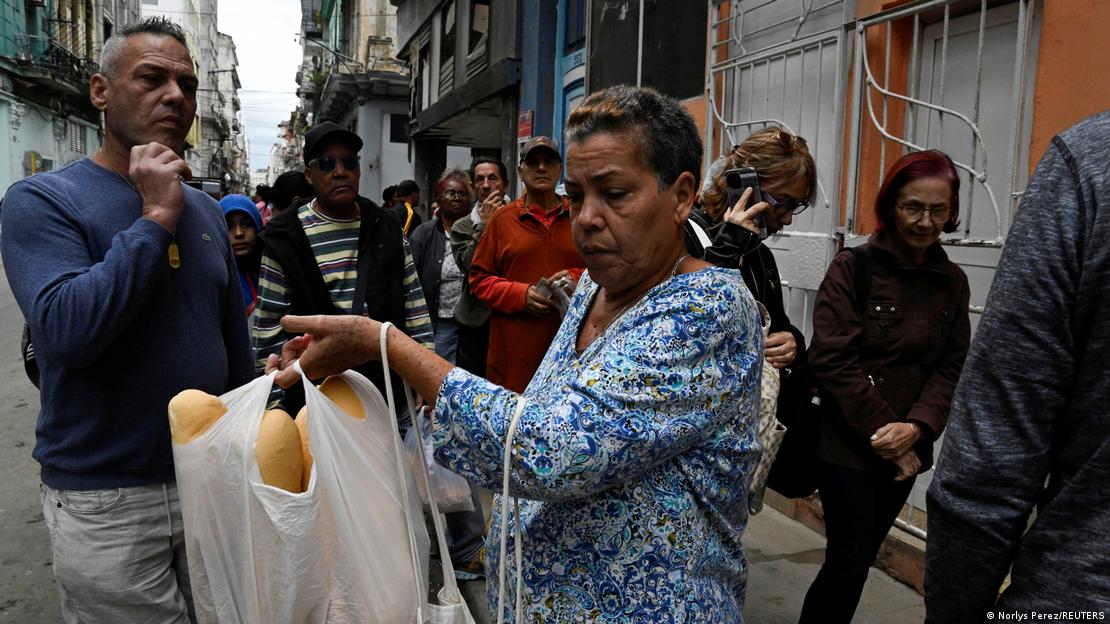 Varias personas hacen fila en La Habana para comprar pan. Una mujer sostiene una bolsa con varios panes dentro. Varias personas hacen fila en La Habana para comprar pan. Una mujer sostiene una bolsa con varios panes dentro.