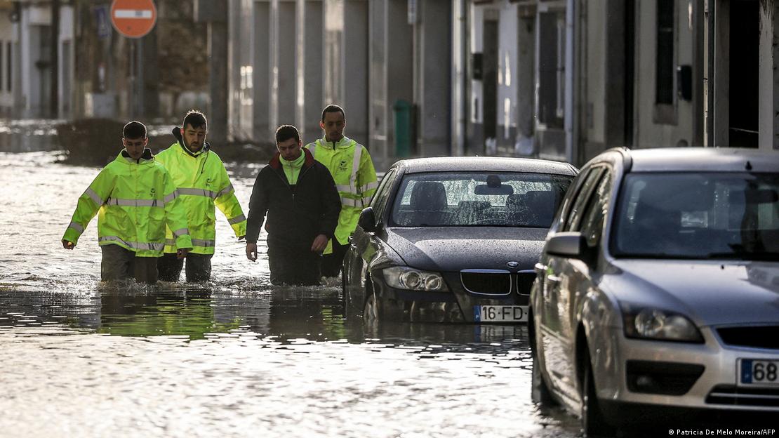 Equipes de emergência caminham em rua alagada após tempestade