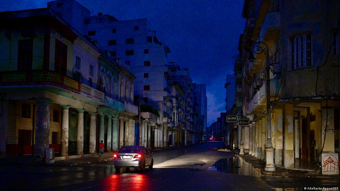 Calle de La Habana a oscuras, iluminada por las luces de un auto. 