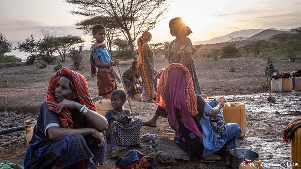 Displaced women and children sit on the ground in Ethiopia's Afar region, with trees visible in the background