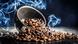 Roasted coffee beans spilling from a cup with smoke in background Roasted coffee beans spilling from a cup with smoke in background