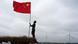 Persona coloca una bandera de China. Persona coloca una bandera de China.
