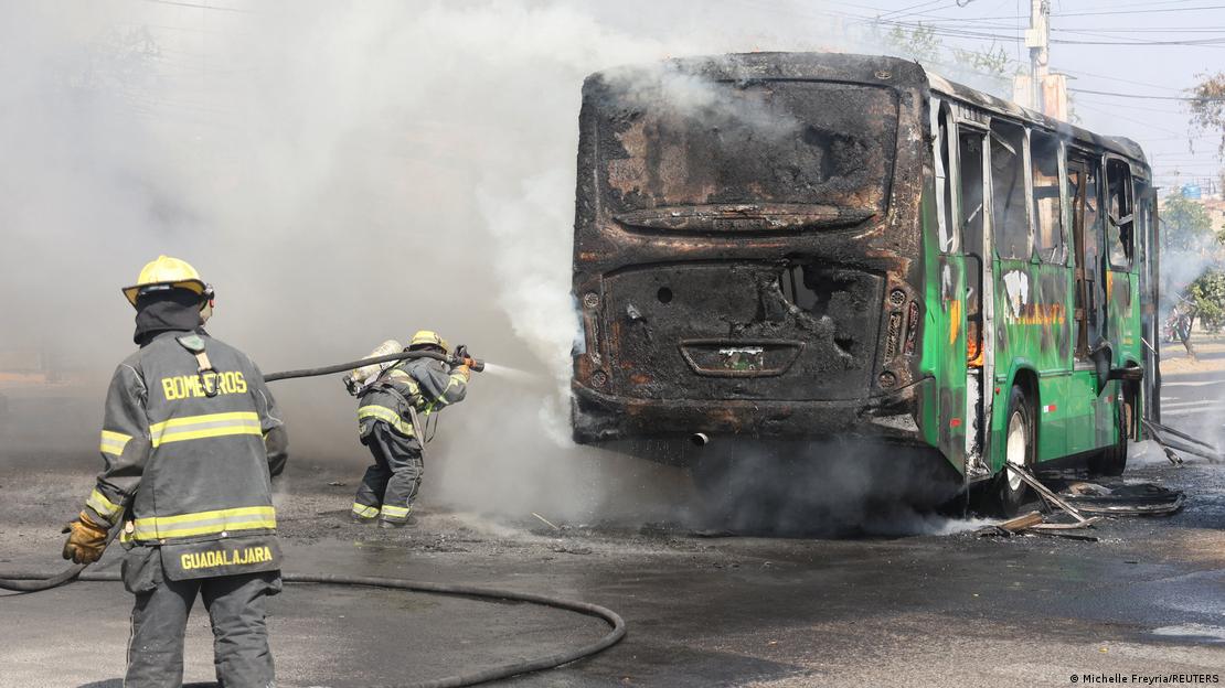 Meksika'nın Guadalajara kentinde ateşe verilen bir otobüsü söndürme çalışmalarını sürdüren Meksika itfaiyesi, 22 Şubat 2026. İki itfaiyeci ve kül olmuş bir otobüs
