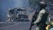 A soldier stands guard by a charred vehicle after it was set on fire A soldier stands guard by a charred vehicle after it was set on fire