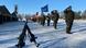 German Bundeswehr soldiers salute and march in the snow carrying numerous flags, three combat rifles can be seen in the foreground German Bundeswehr soldiers salute and march in the snow carrying numerous flags, three combat rifles can be seen in the foreground