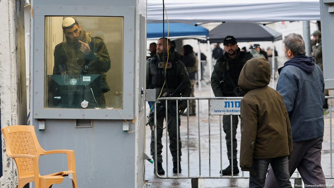 Palestinos se aproximam de uma guarita em um posto de controle israelense na Cisjordânia