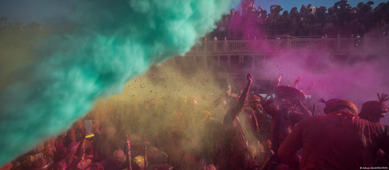 Above a dancing crowd, clouds of turquoise, yellow and pink mist swirl.