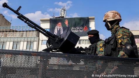 Вооружени ирански војници, зад нив е знаме со насликаниот лик на Али Хаменеи 