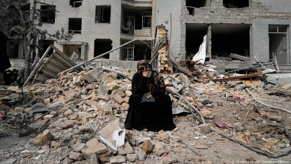 Tahran'da bombalanan bir binanın ankazında oturan bir kadın