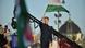 Peter Magyar, in a dark suit with traditional Hungarian detail, waves a Hungarian flag while speaking on stage