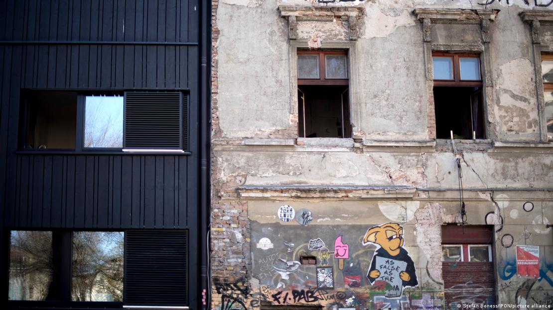 Novo projeto de construção ao lado de uma casa ocupada ilegalmente e coberta de grafite Novo projeto de construção ao lado de uma casa ocupada ilegalmente e coberta de grafite
