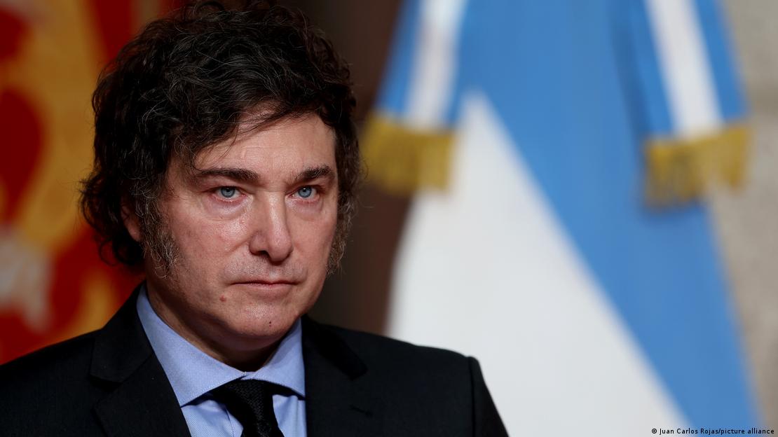 Primer plano de rostro de Javier Milei, presidente de Argentina. Detrás, bandera argentina.