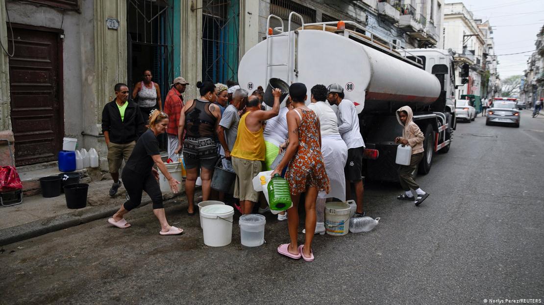 Havana'da Kübalılar bir su tankerinden kovalarla su almak için bekliyor