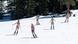 Cinco mujeres en traje de baño descienden con sus esquíes por una pista de nieve. Cinco mujeres en traje de baño descienden con sus esquíes por una pista de nieve.