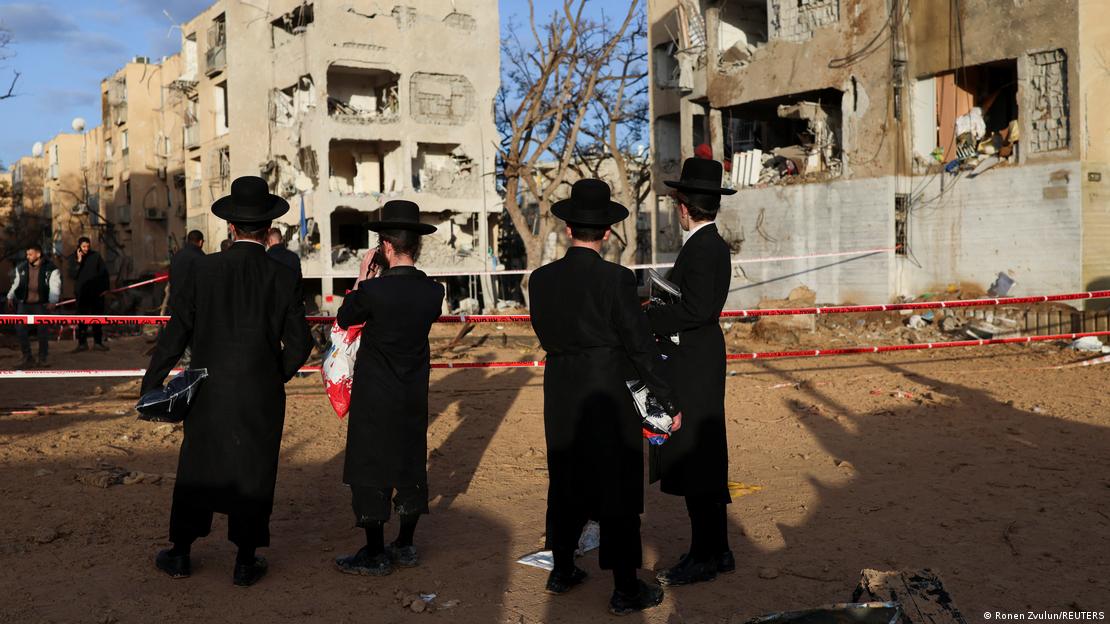 İsrail'in güneyindeki Arad'a düzenlenen saldırı sonucu hasar gören binaların önünde duran İsraillliler 