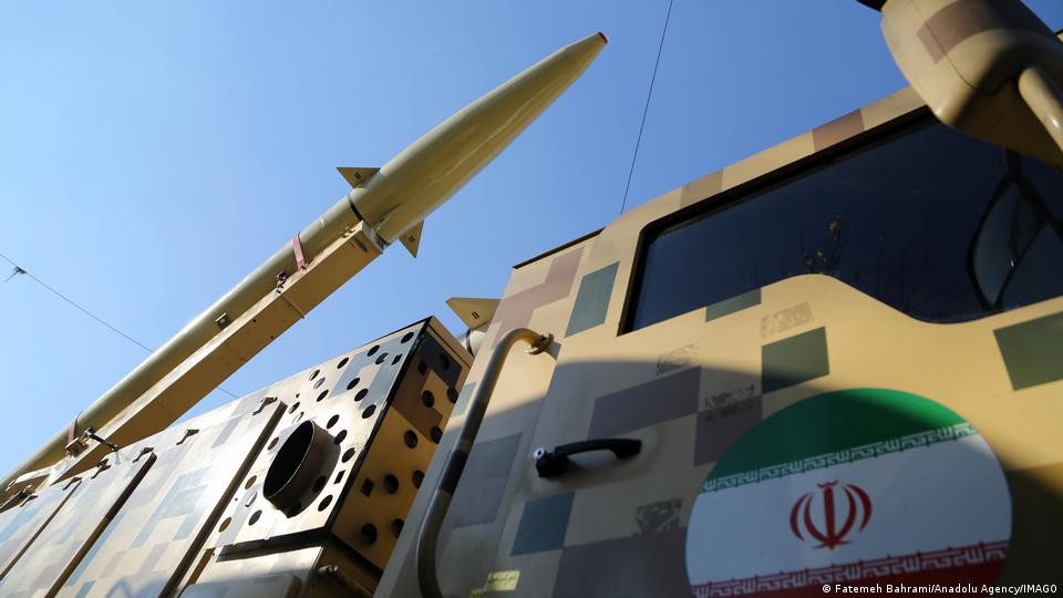 تصویر پرچم جمهوری اسلامی و یک خودروی نظامی حامل موشک بالستیک