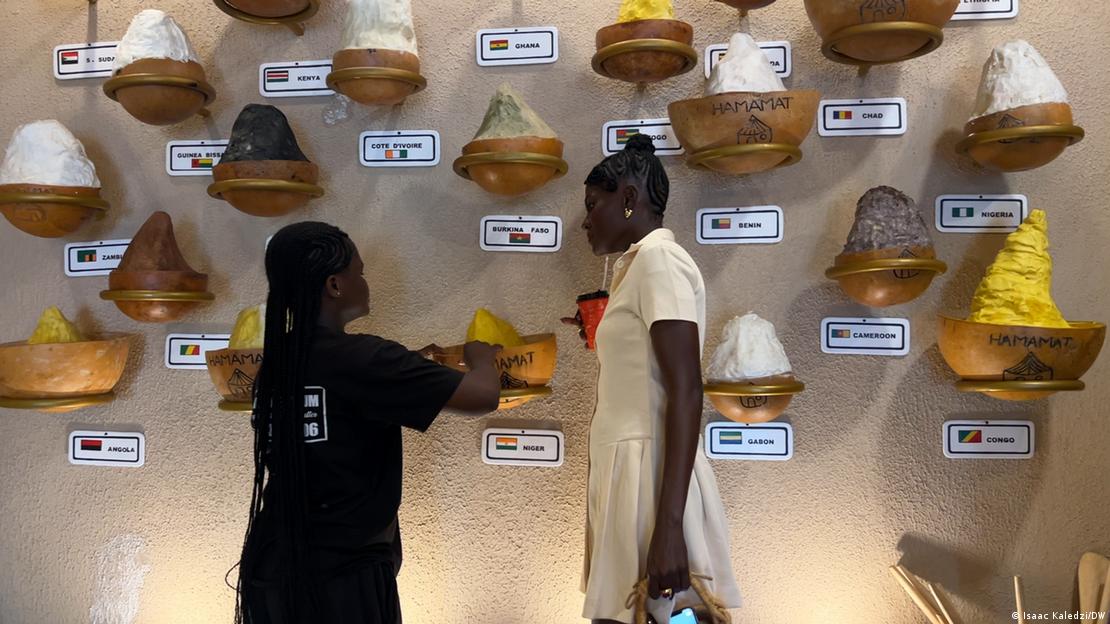 Ghana Accra 2026 | Sheabutter-Museum (deux jeunes visiteuses devant des récipient contenant du beurre de karité accrochés au mur)