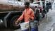 Hombre transportando cubos. Camión cisterna con agua aparcado en la calle. Hombre transportando cubos. Camión cisterna con agua aparcado en la calle.
