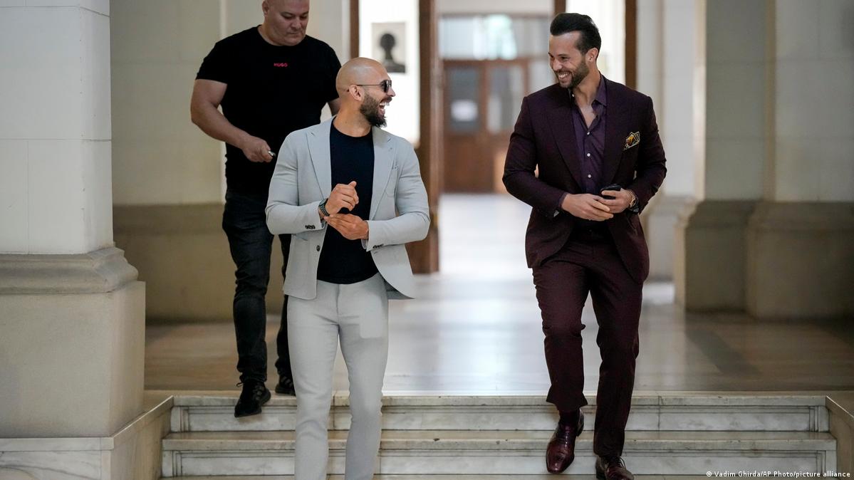 Andrew Tate smiles while waiting along with his brother Tristan, right, for a hearing inside the Court of Appeals building in Bucharest, Romania