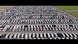 Aerial view of a vast parking lot filled with hundreds of cars arranged in long, orderly rows. Aerial view of a vast parking lot filled with hundreds of cars arranged in long, orderly rows.