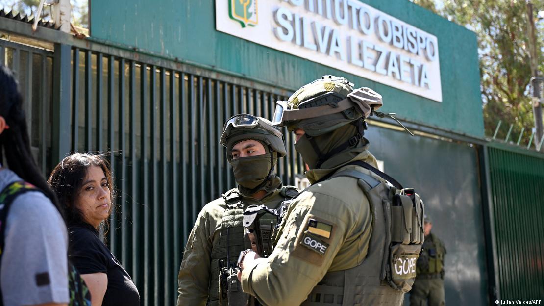 Dos uniformados con una mujer frente a un colegio de Chile.