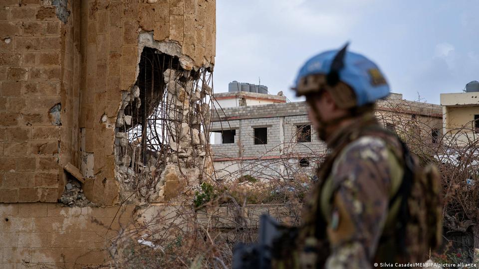 جنوبی لبنان میں اسرائیلی حملوں سے تباہ شدہ عمارات اور اقوام متحدہ کے یونیفل امن دستوں کا ایک فوجی اپنا نیلا ہیلمٹ پہنے ہوئے