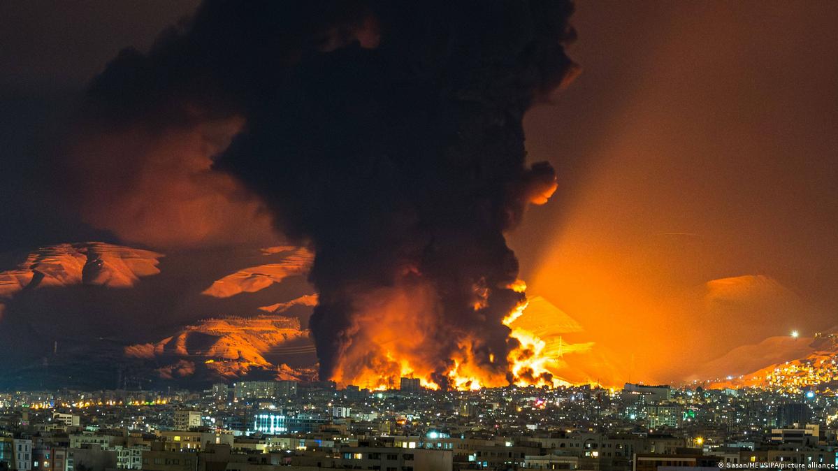 A red sky over a huge urban area as smoke and flames rise from an air attack on an oil depot, Tehran, Iran