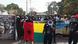 Protesters hold the flag of Guinea Bissau and a poster showing Vigario Balanta and walk along the road. Protesters hold the flag of Guinea Bissau and a poster showing Vigario Balanta and walk along the road.
