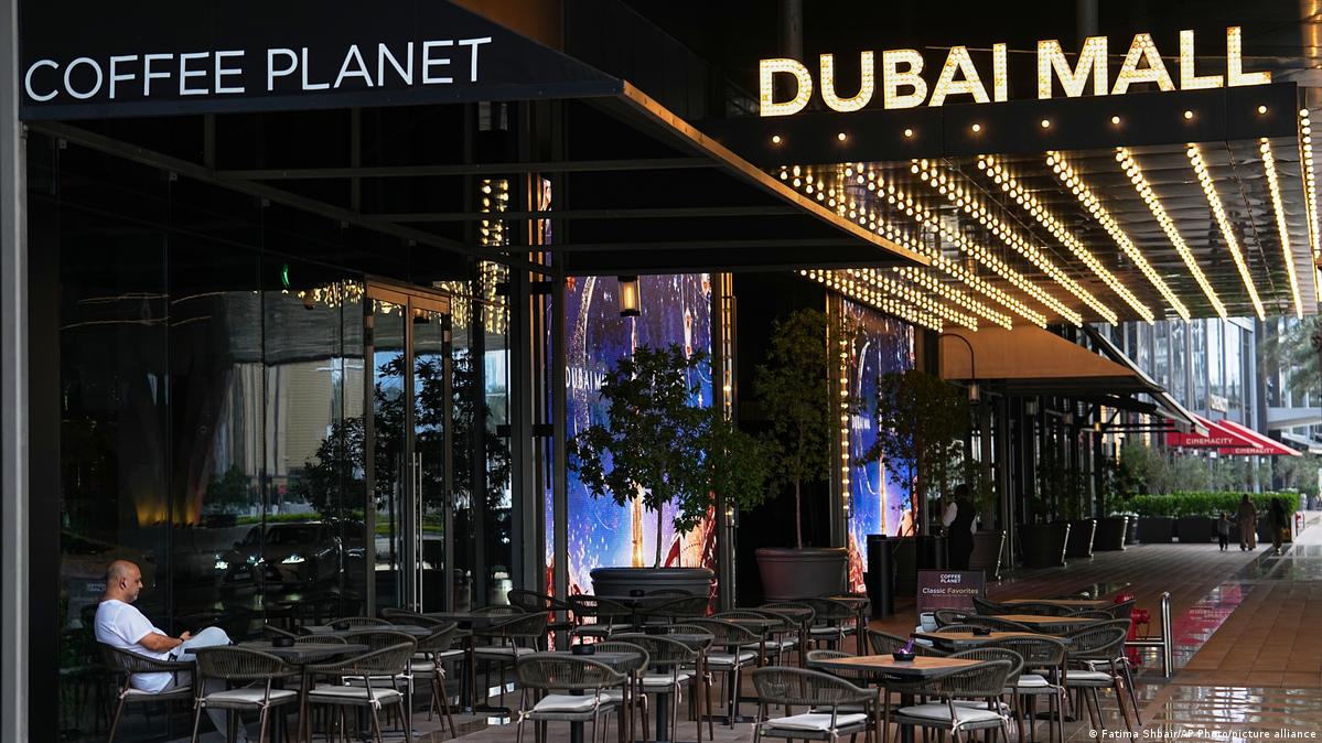 A man sits at an outdoor empty cafe in downtown Dubai, United Arab Emirates